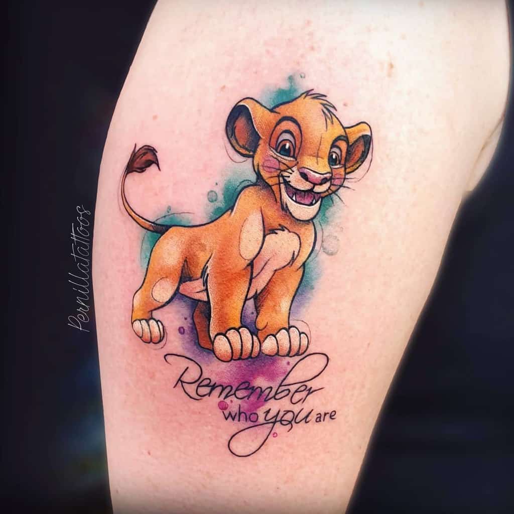 A vibrant Simba tattoo with the quote "Remember who you are" beneath, symbolizing strength and identity from The Lion King