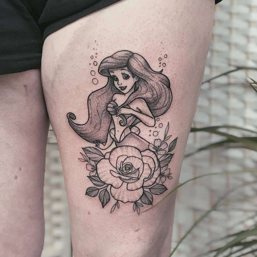 A beautiful black and white tattoo of Ariel from The Little Mermaid, surrounded by delicate rose flowers