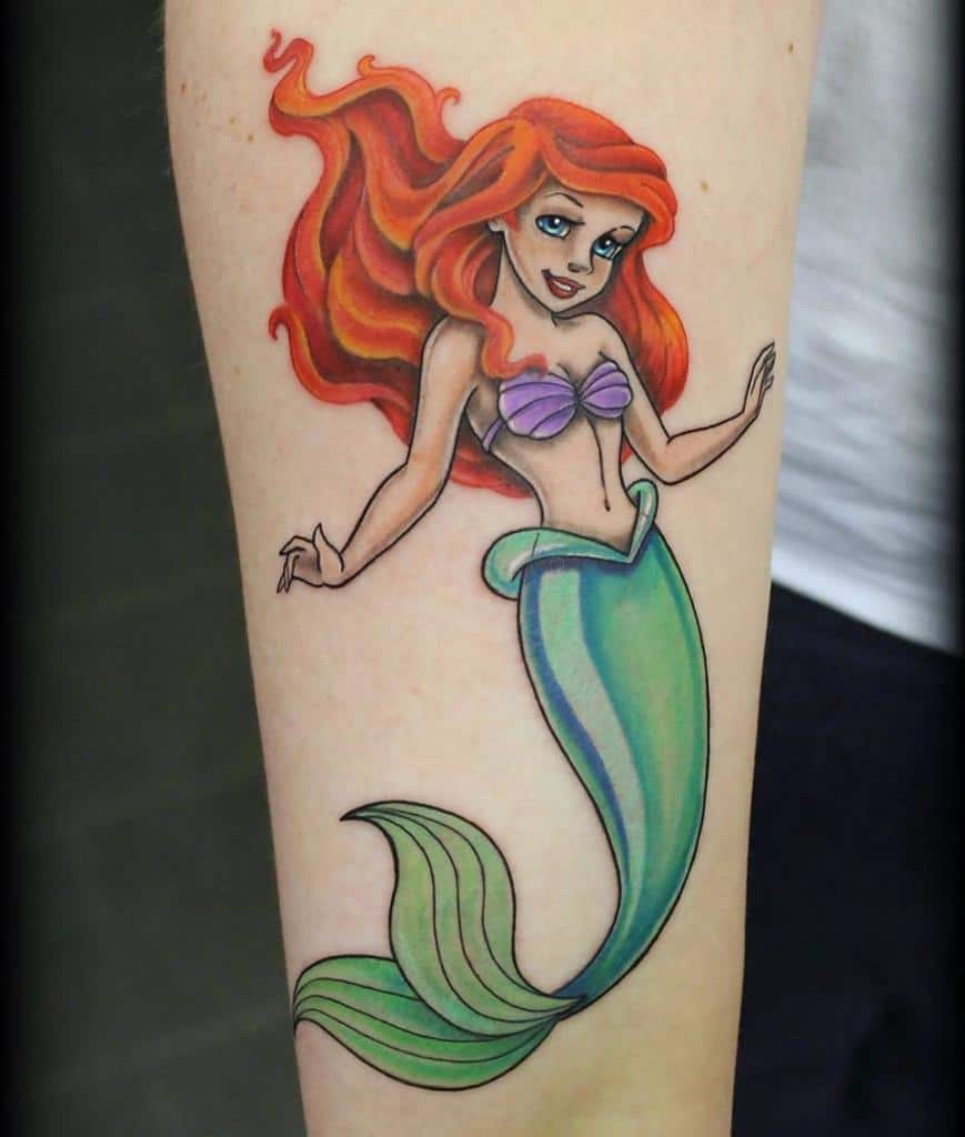 A colorful and vibrant tattoo of Ariel from The Little Mermaid, showcasing her signature red hair and flowing tail, capturing her joyful spirit