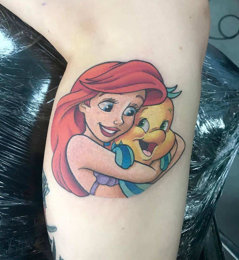 A joyful tattoo depicting Ariel and Flounder sharing a heartwarming embrace, capturing their special bond