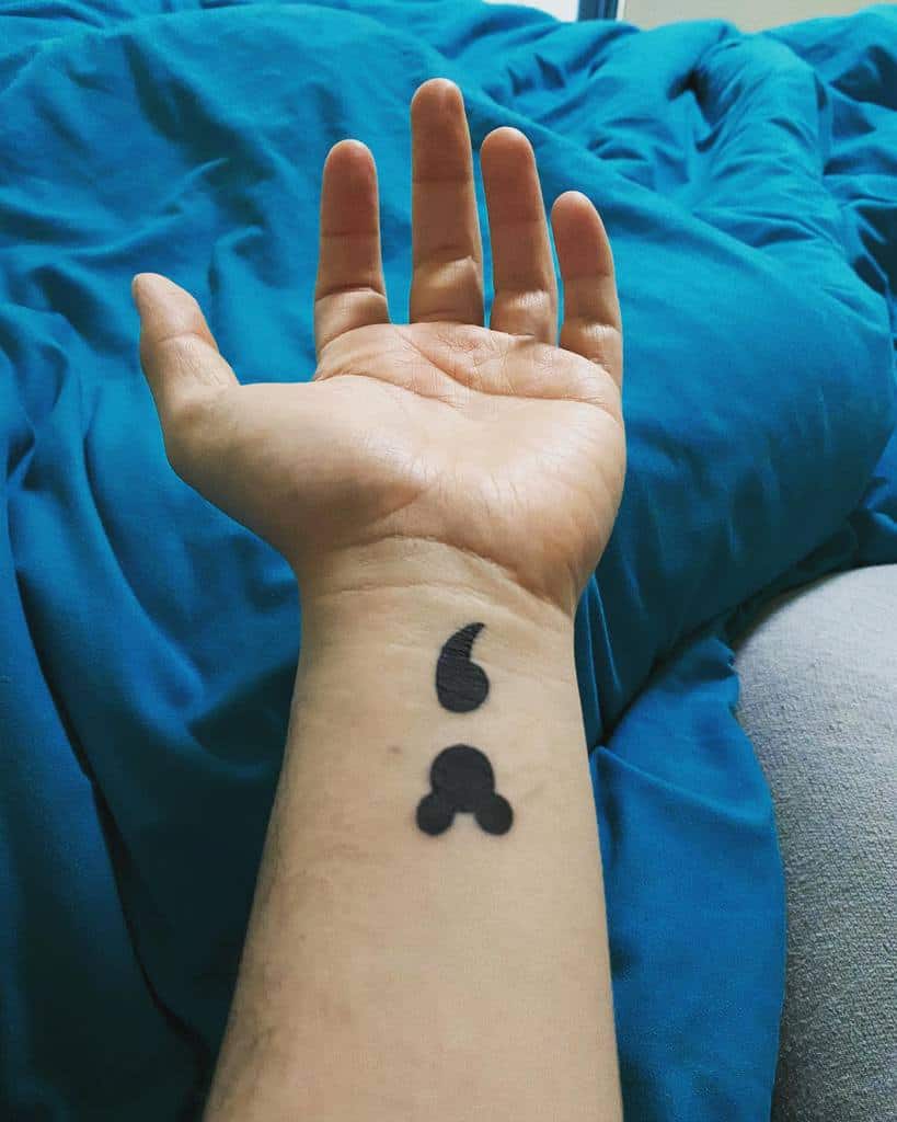 A minimalistic yet impactful tattoo, featuring a clever Disney reference with a Mickey Mouse-shaped semicolon