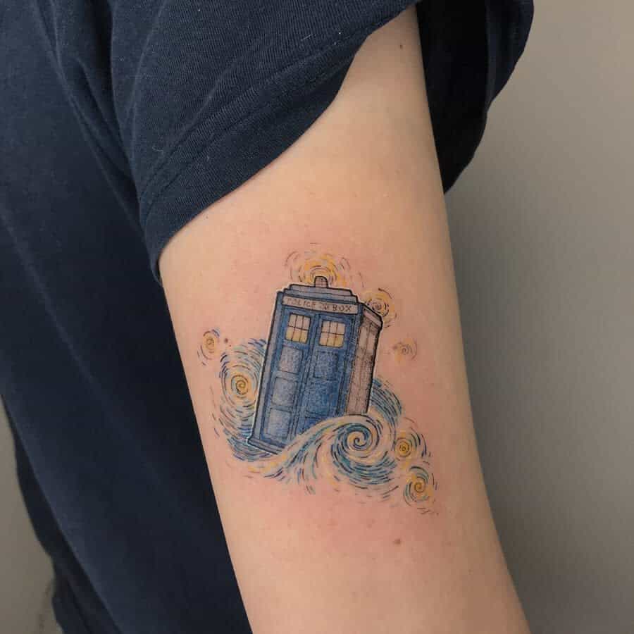 Delicate tattoo depicting the TARDIS from 'Doctor Who', enhanced with soft blue swirls and golden accents that evoke a sense of motion and magic