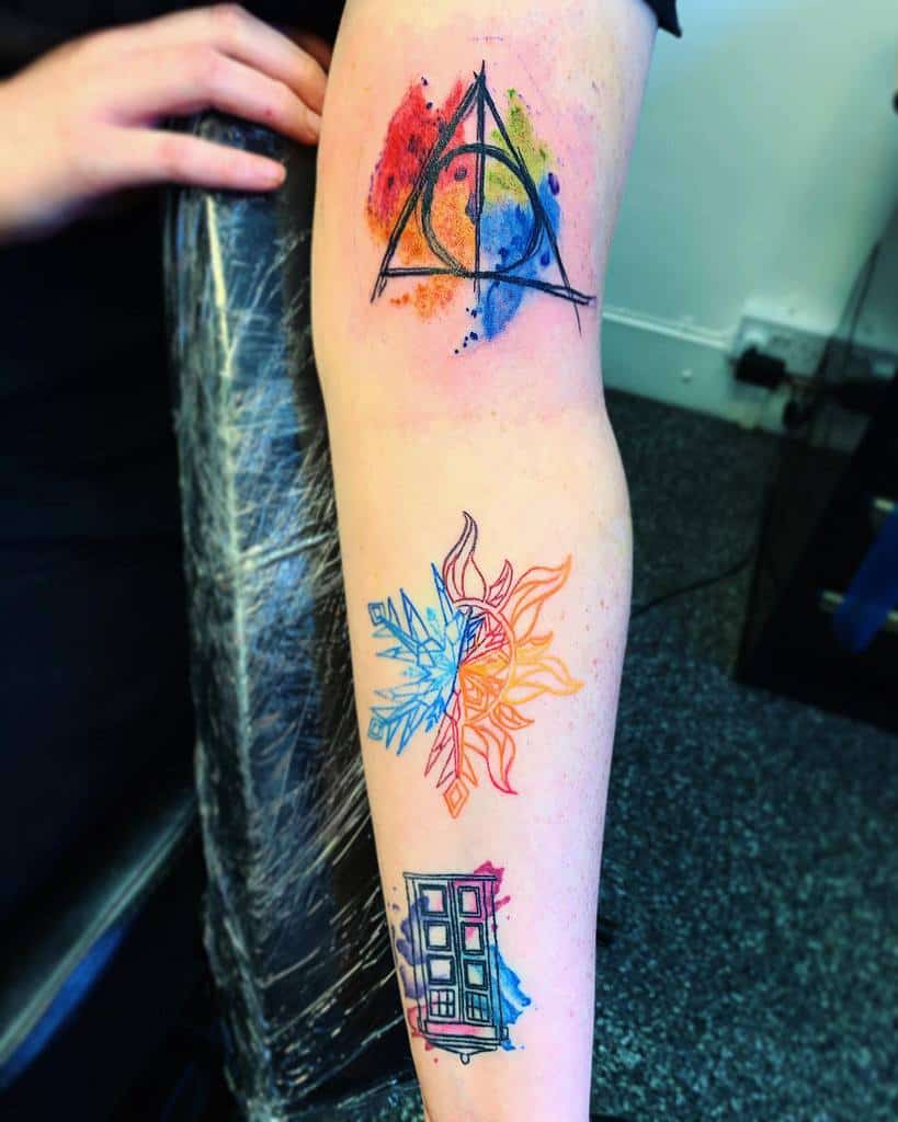 Vibrant tattoo featuring an array of colorful symbols, including a TARDIS from 'Doctor Who', alongside a magical array and mystical elements, each depicted in a splash of watercolor style