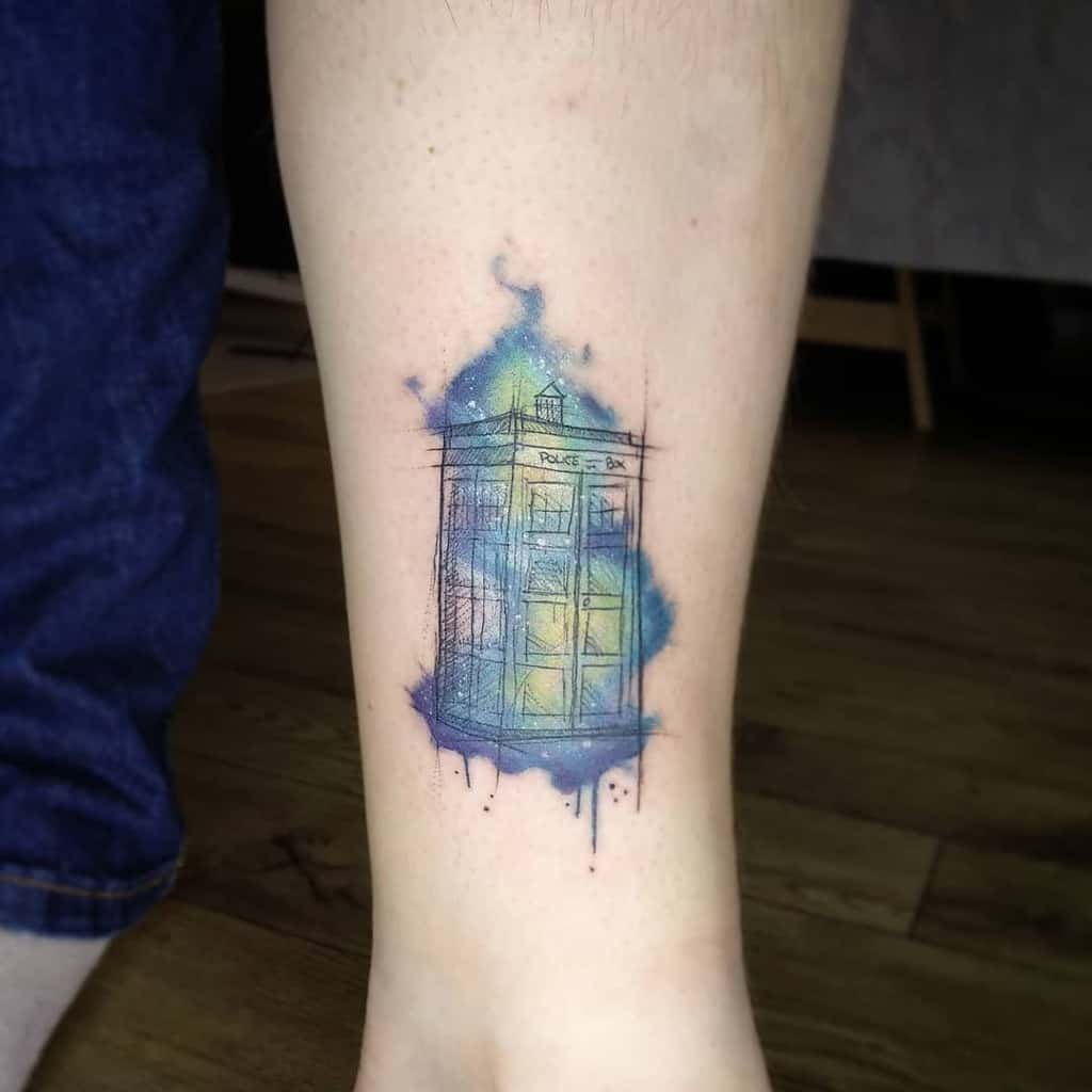 Colorful Doctor Who tattoo featuring the TARDIS with vibrant yellow and blue watercolor effects and ink splashes