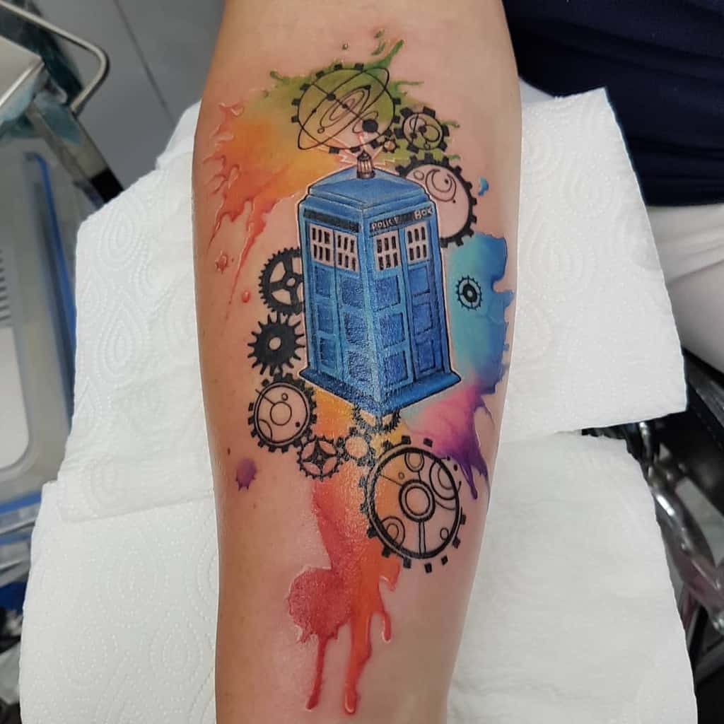Vivid Doctor Who themed tattoo, showcasing the TARDIS with a backdrop of multicolored watercolors and floating gears