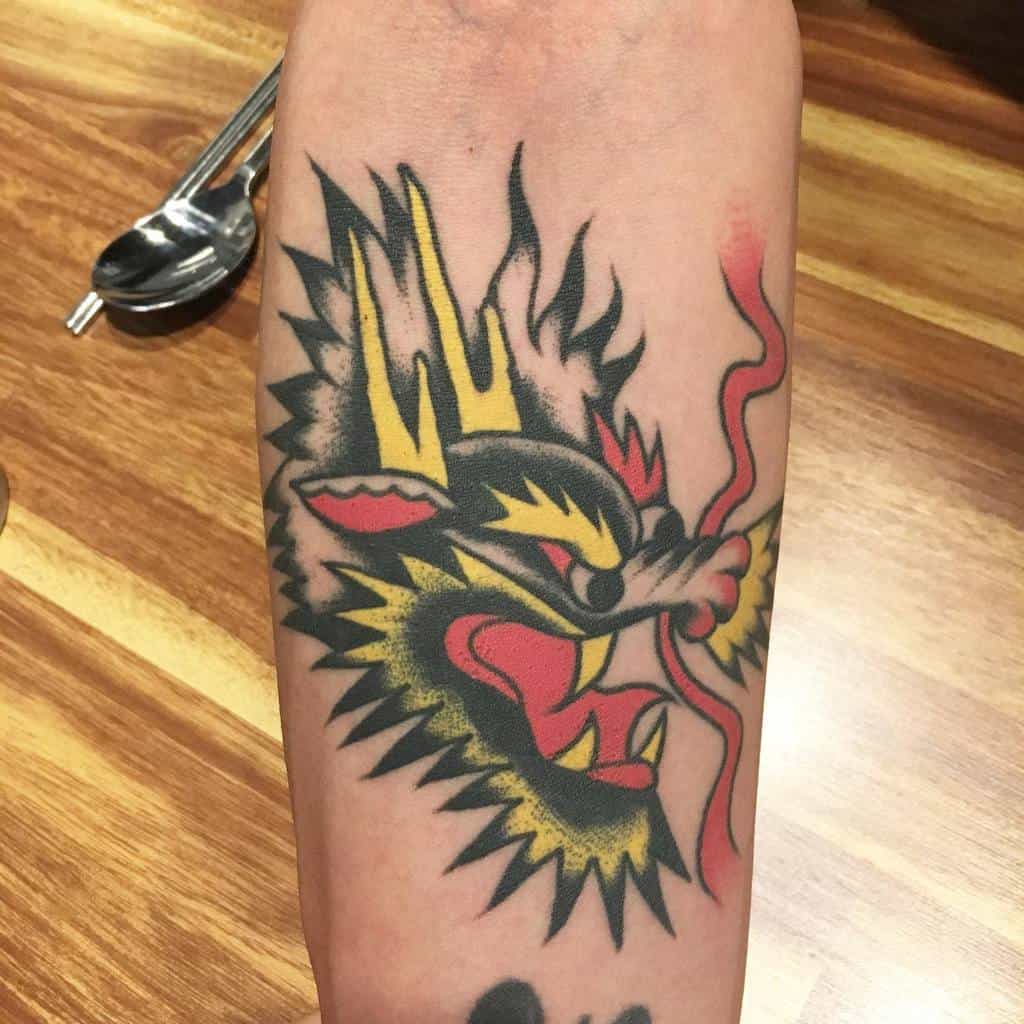 A vibrant traditional tattoo of a dragon's head, with flames dancing around its colorful form, adorns the arm