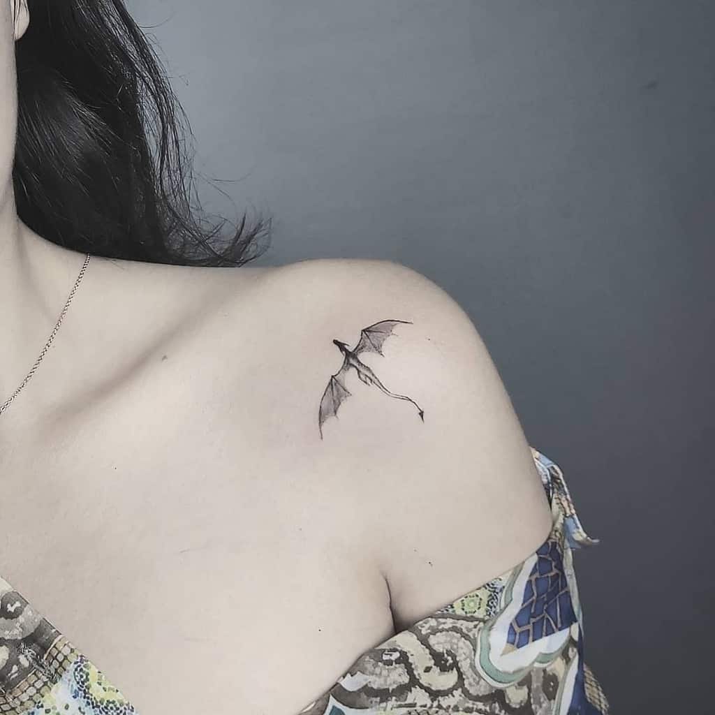 A small dragon tattoo on woman's shoulder