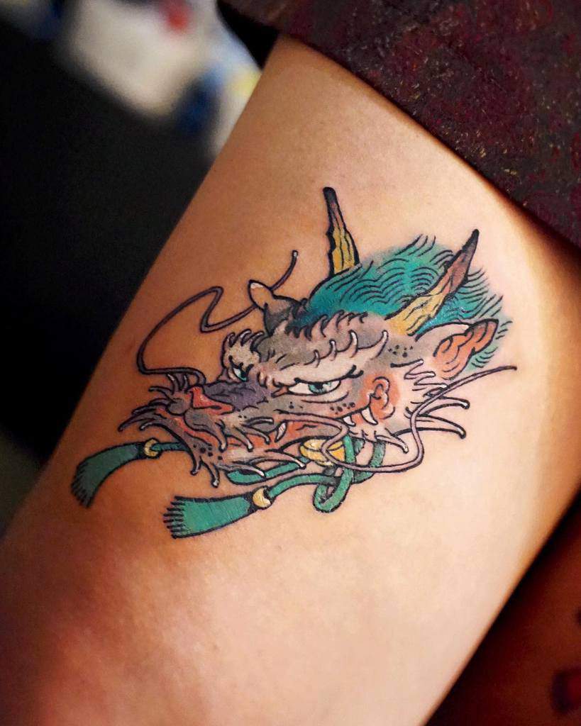 Tattoo of a detailed dragon head with blue accents on skin