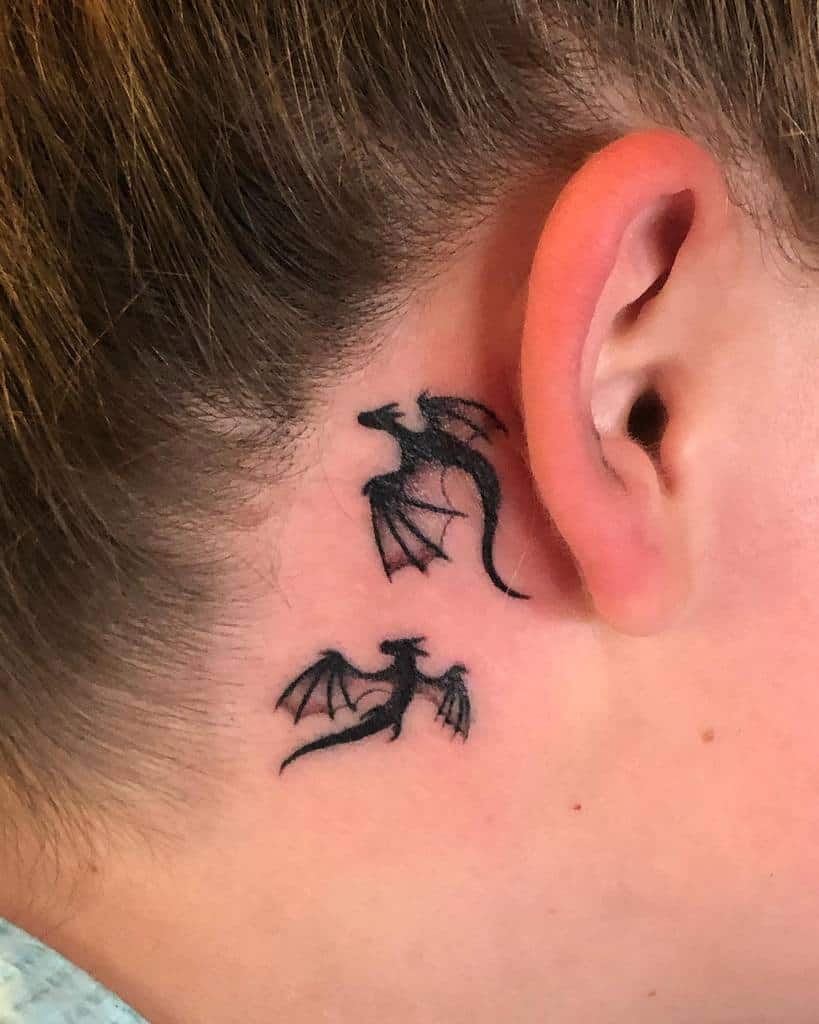 Two small dragon tattoos behind an ear
