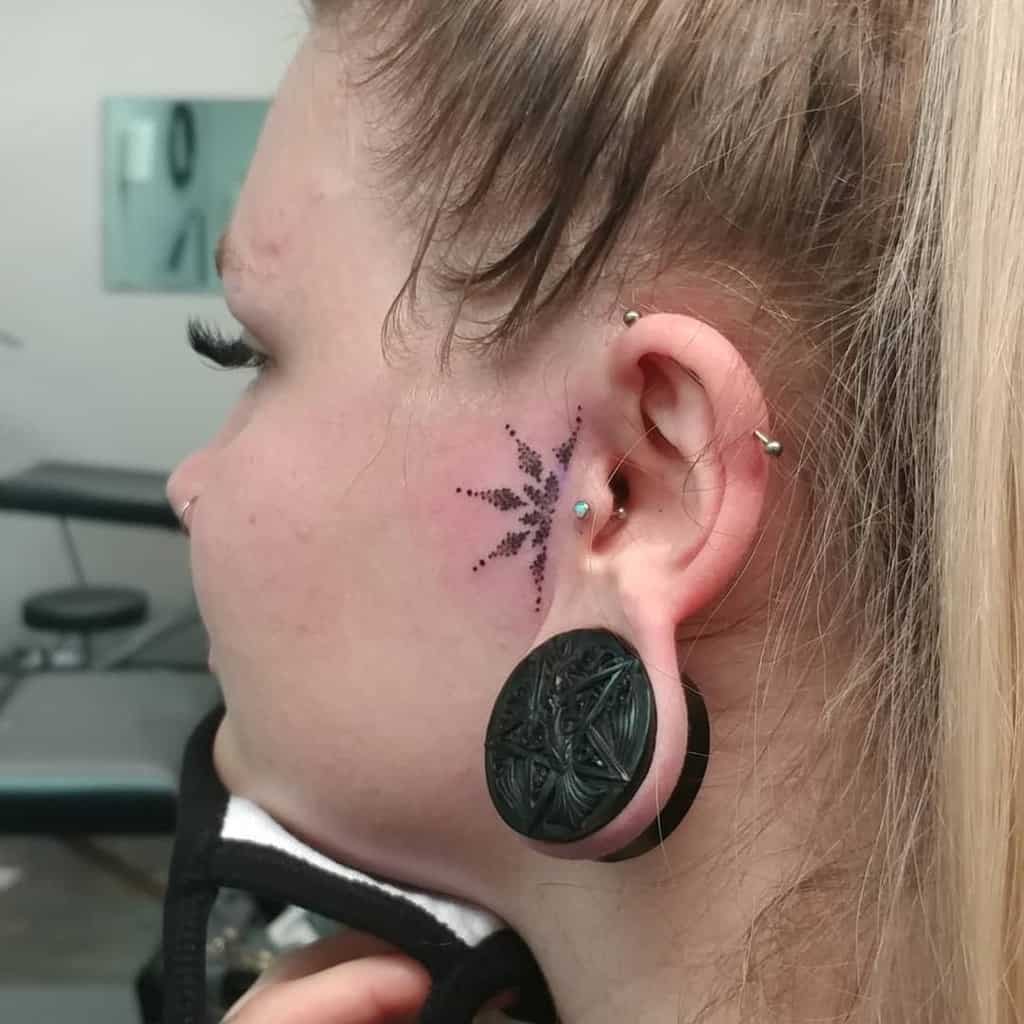 Geometric dotwork tattoo near the ear, resembling a starburst or abstract pattern, adding a bold and edgy accent to the face