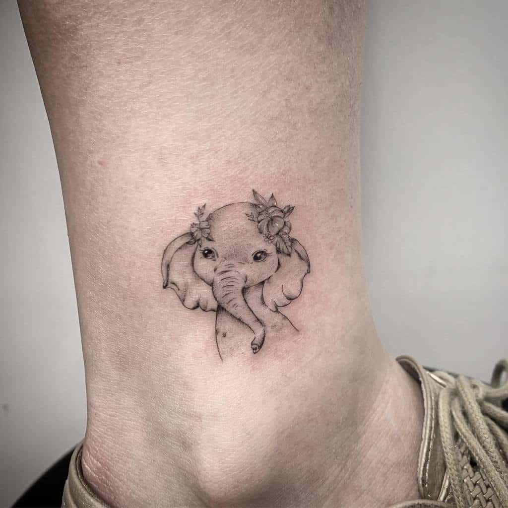 Tattoo of an elephant with floral accents on an ankle