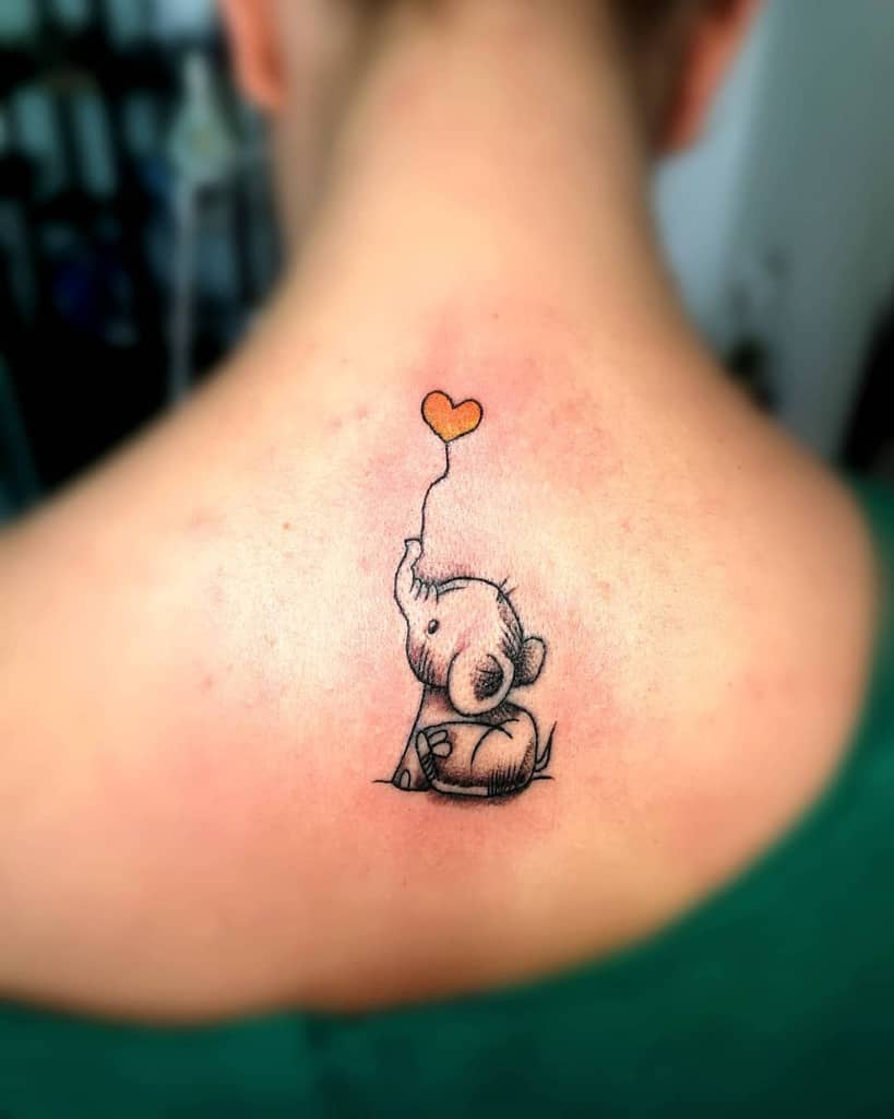 Tattoo of a baby elephant holding a heart-shaped balloon on upper back