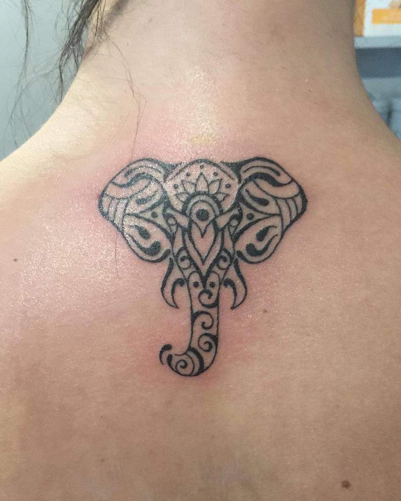 Ornate elephant tattoo on the back of a person's neck, featuring intricate swirl and dot patterns