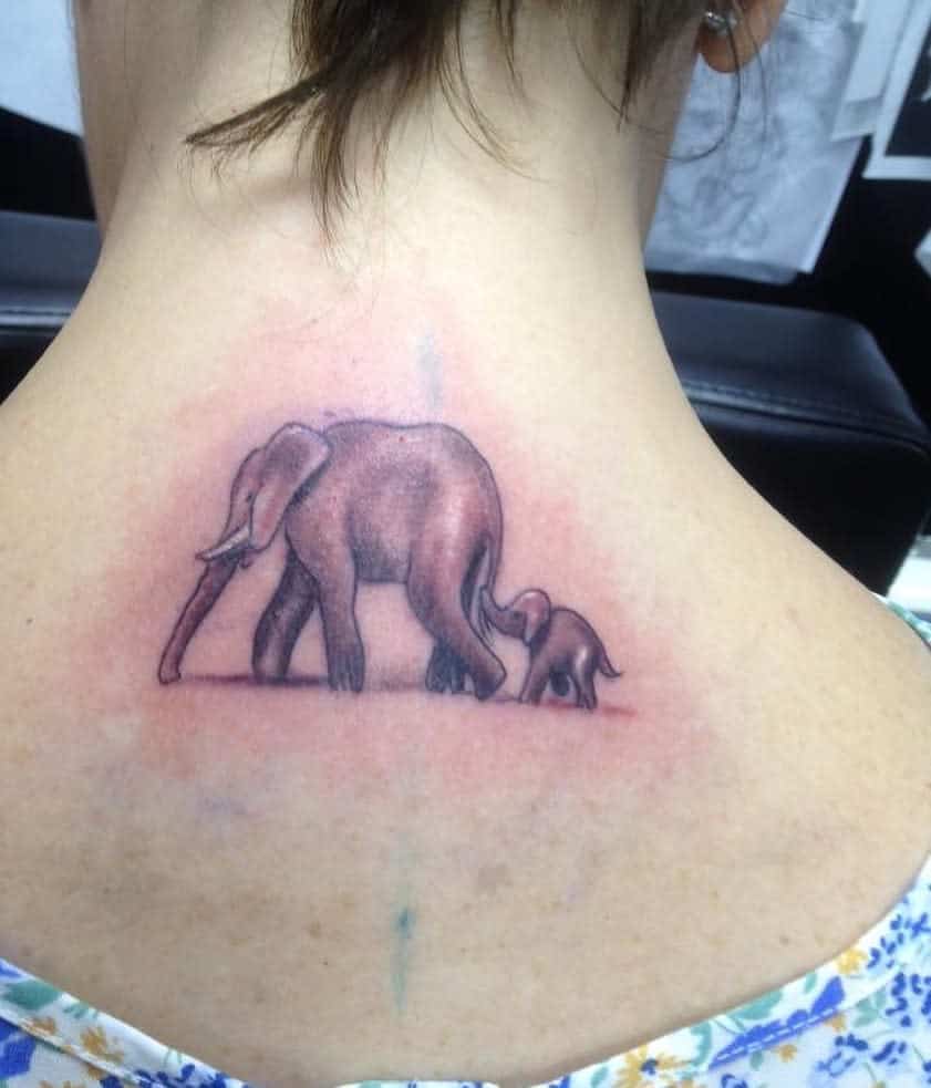 Tattoo of a mother elephant and calf walking together on the back of a  neck