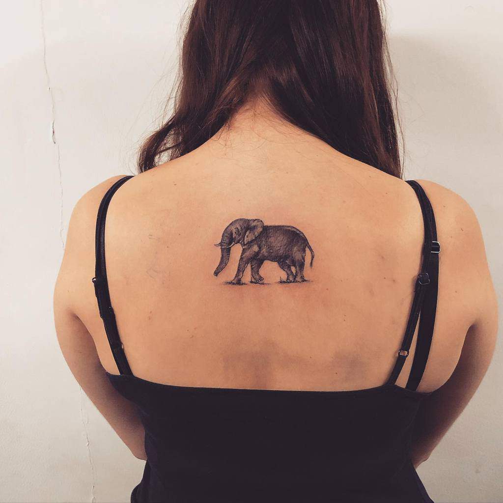 A woman with a black elephant tattoo on her upper back