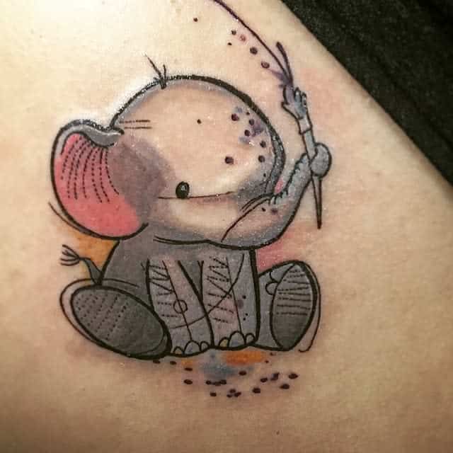 A cute cartoon elephant tattoo holding a dandelion on skin