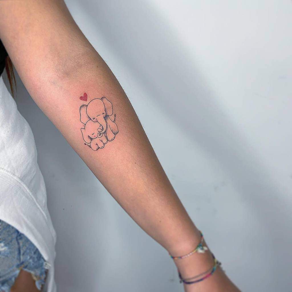 Person with an elephant and calf tattoo on their forearm, a small heart above the elephants