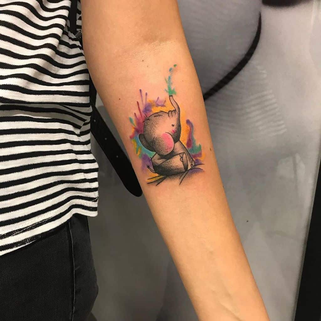 Colorful tattoo of a baby koala on the inner forearm, set against a vibrant watercolor splash