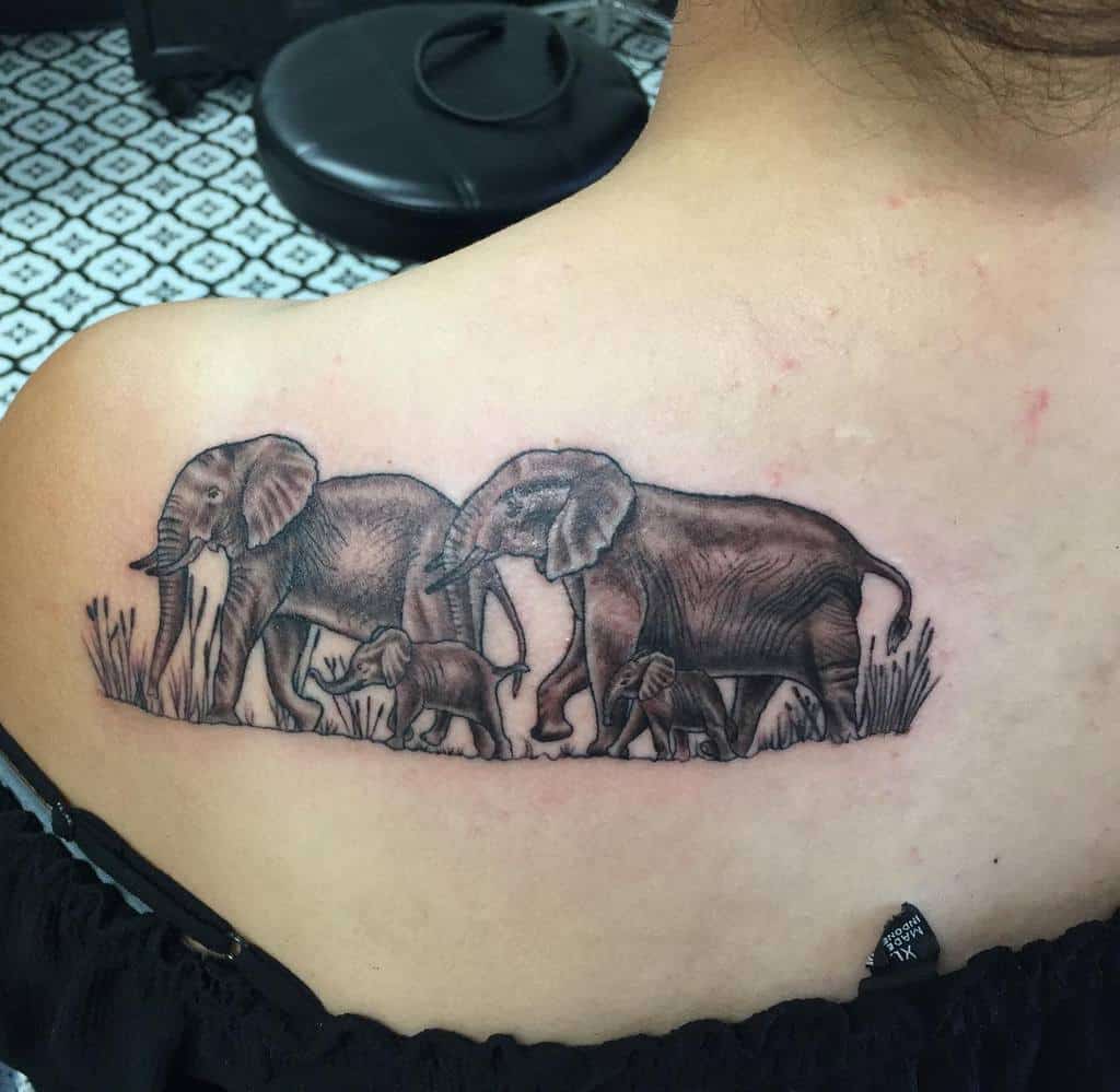 Tattoo of a family of elephants walking in a line on a back