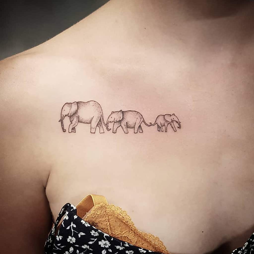 A tattoo of three elephants walking in a line on an upper chest near the shoulder