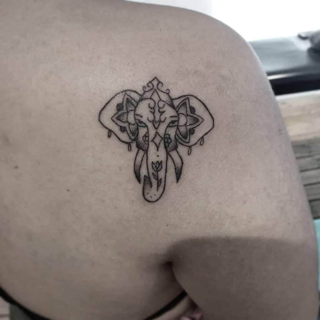 Elephant head tattoo with floral designs on an upper back