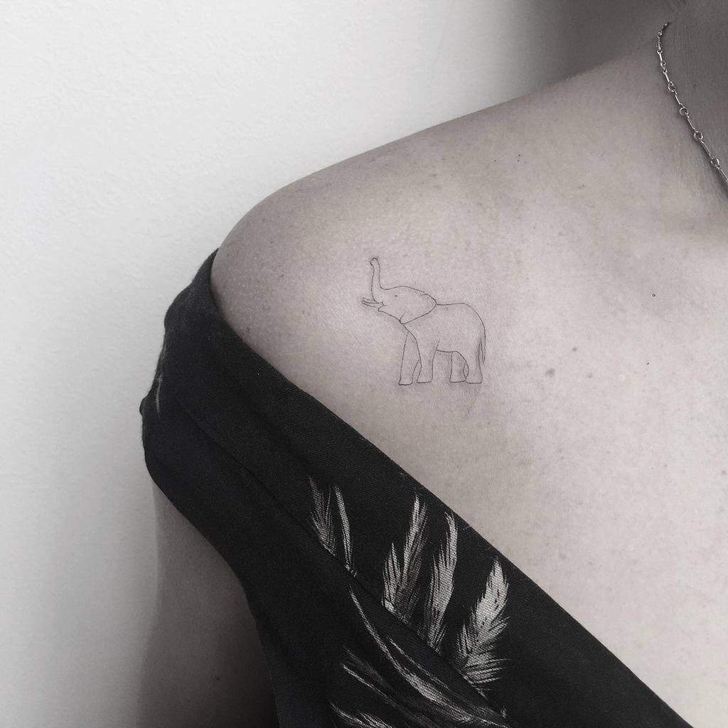 Minimalist outline elephant tattoo on a shoulder