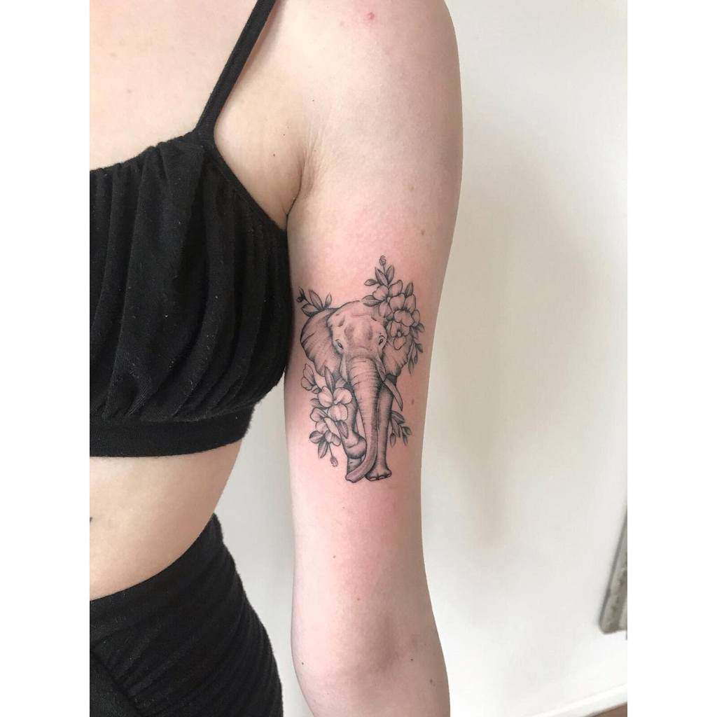 Arm tattoo of an elephant surrounded by flowers on a woman