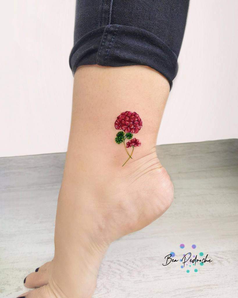 Colorful flower tattoo on ankle above foot with red petals and green stem