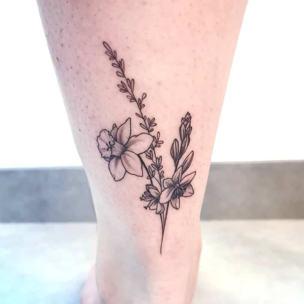 Black line tattoo of daffodils and lavender on a leg