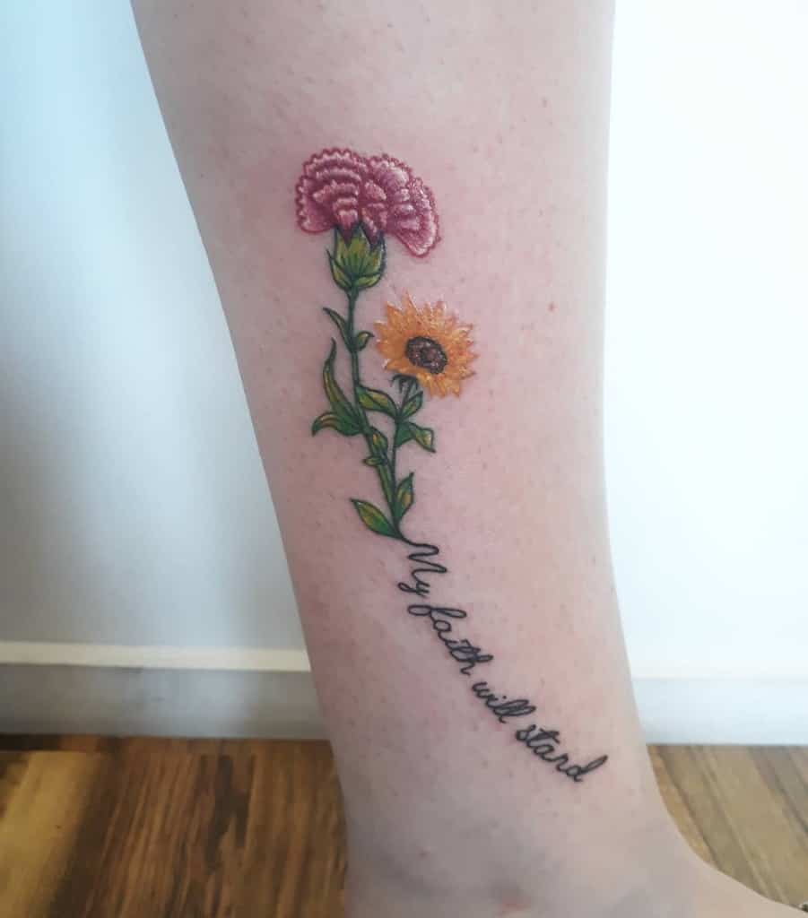 Tattoo of a pink flower, a yellow sunflower, and the phrase "my faith will stand" on a leg