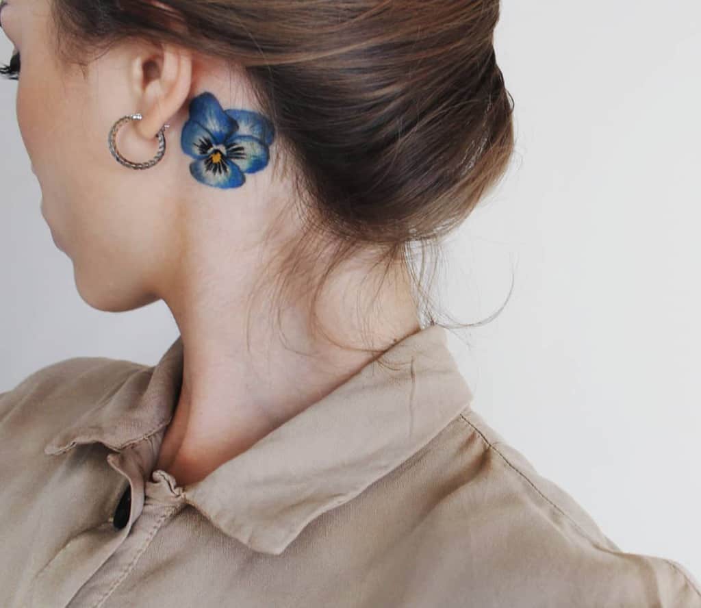 Woman with a blue flower tattoo behind her ear