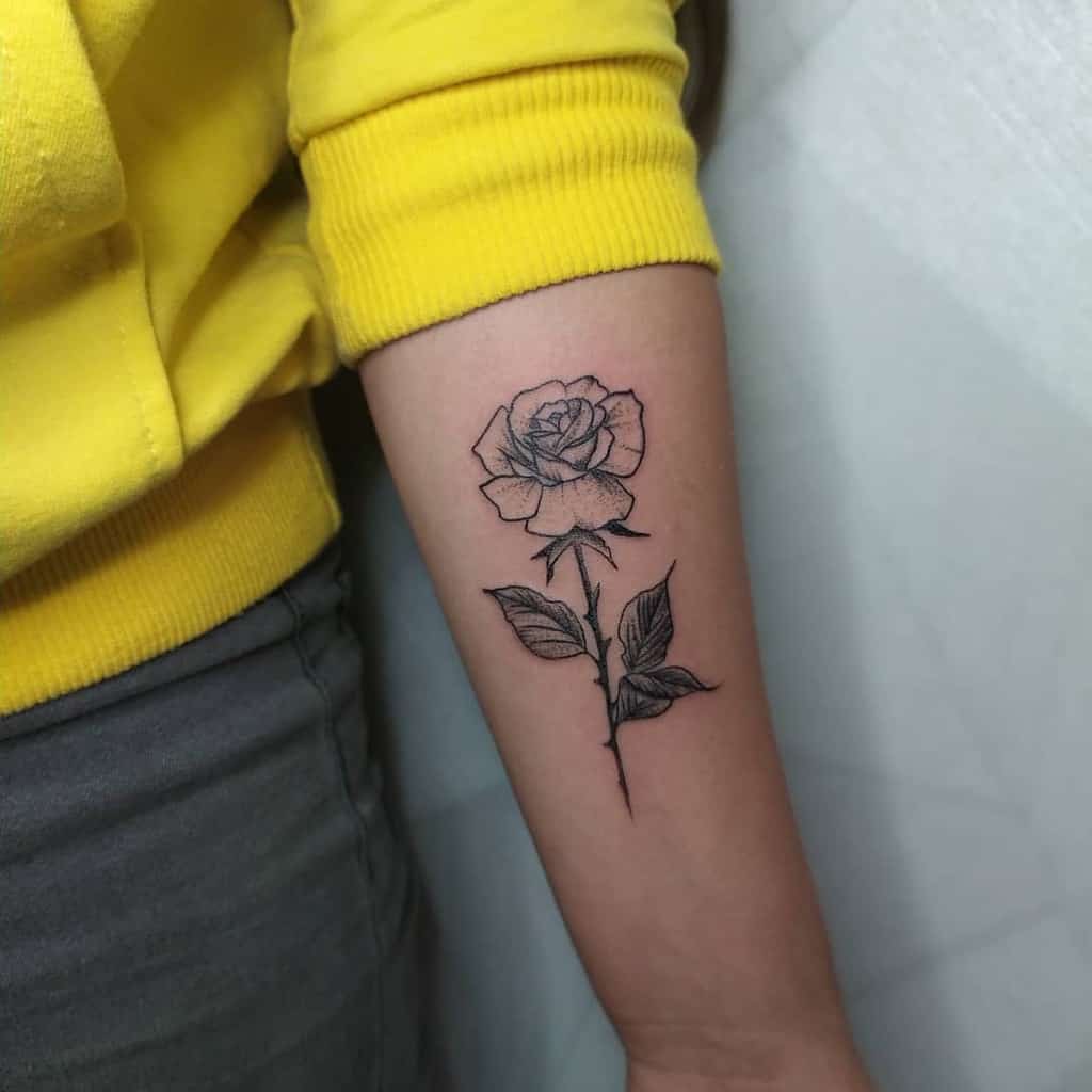 A black ink rose tattoo on a person's forearm