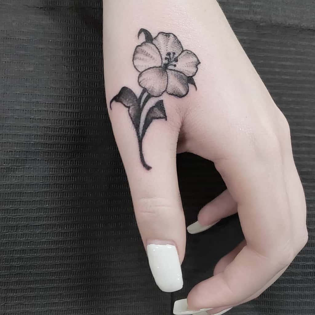 A hand with a black flower tattoo on the thumb