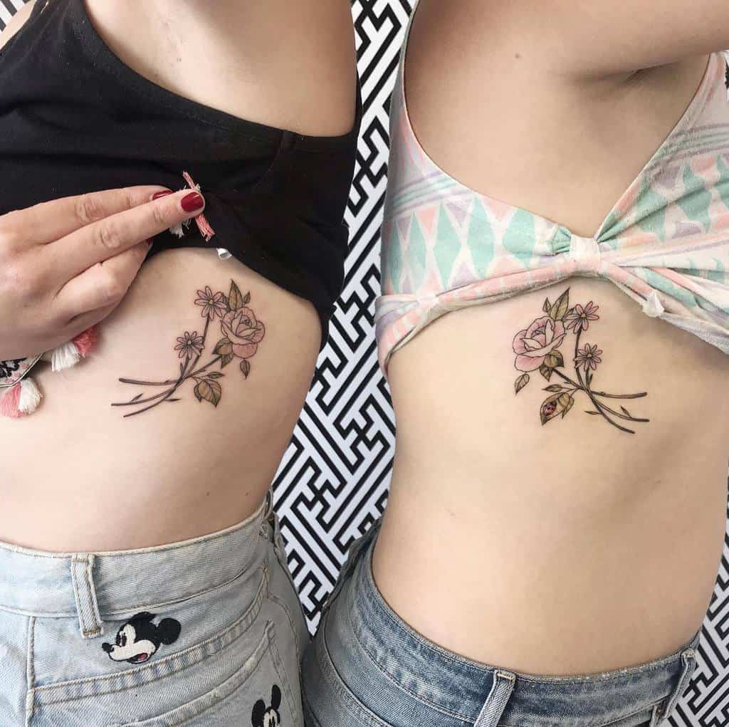 Two women show matching floral tattoos on their sides