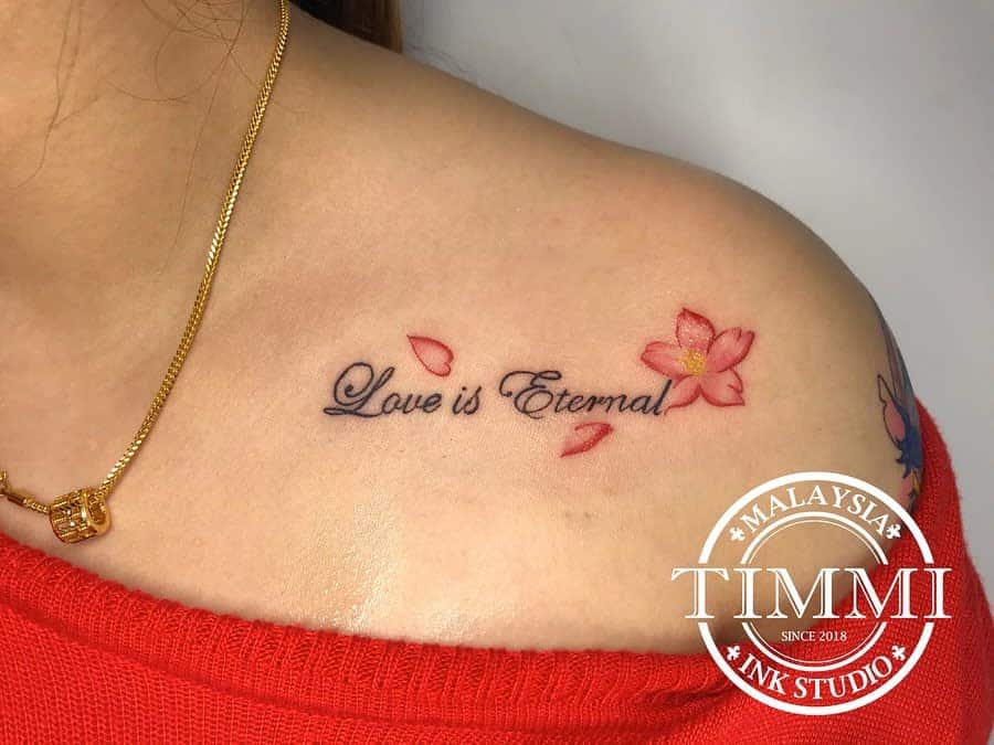 Tattoo on shoulder with "Love is Eternal" text and pink flower petals