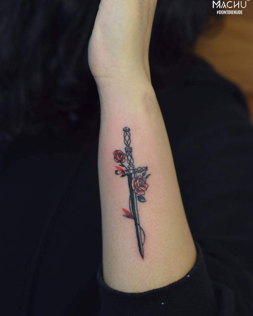Tattoo of a dagger with red roses on a forearm