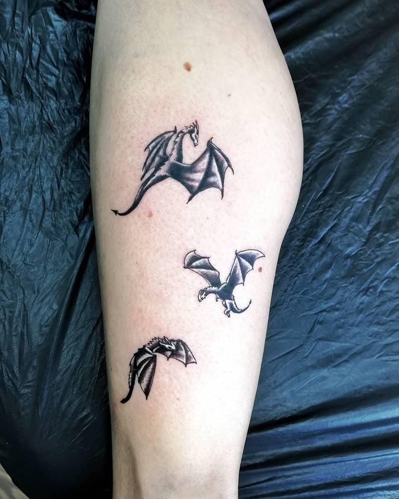 Leg tattoo with three black flying dragons