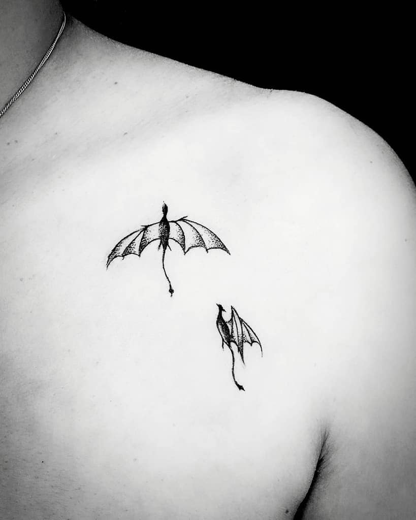 Minimalist dragon tattoos on a person's shoulder