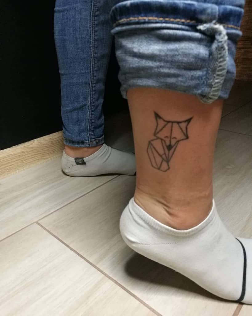 Geometric fox tattoo elegantly placed on the back of a person's ankle, intricately detailed with sharp lines