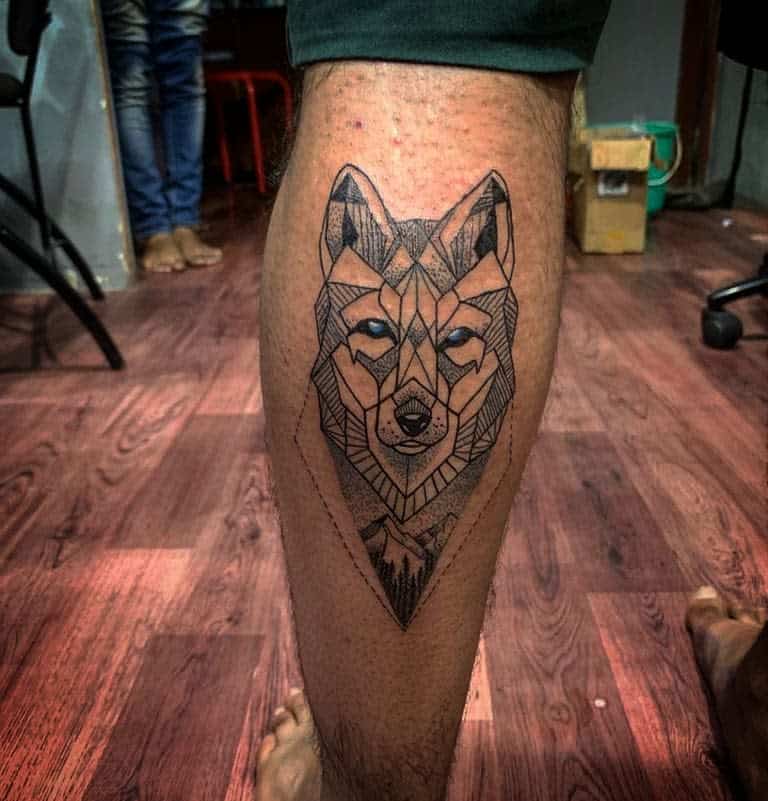A striking geometric wolf tattoo adorns the person's calf