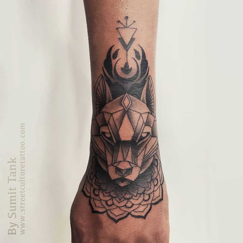 Geometric wolf and fox tattoo with abstract shapes on a forearm