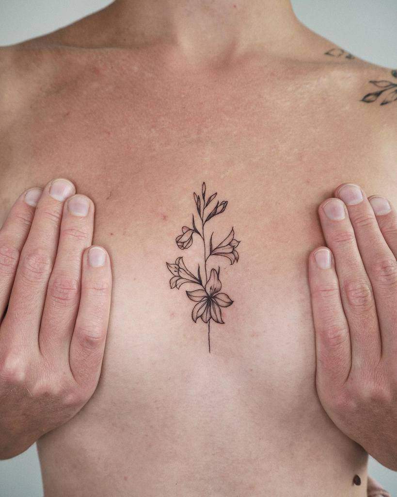 Hands framing a captivating gladiolus tattoo on the chest