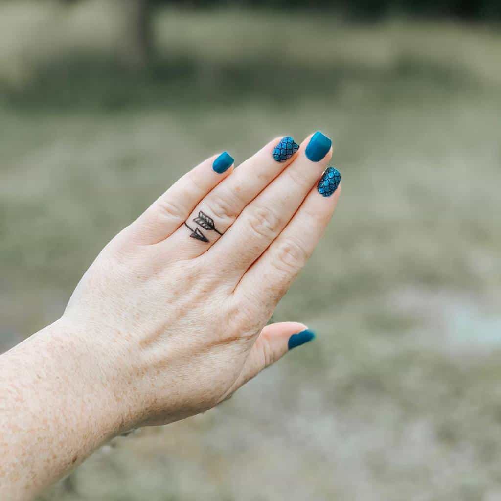 Minimalist finger tattoo of a geometric mountain design, symbolizing strength and adventure, placed subtly on the ring finger