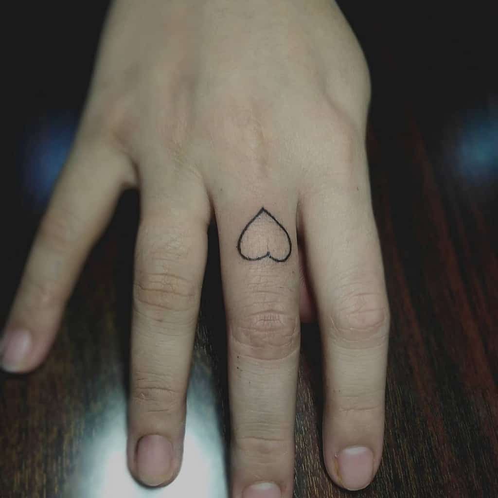 Hand with a small heart tattoo on the middle finger