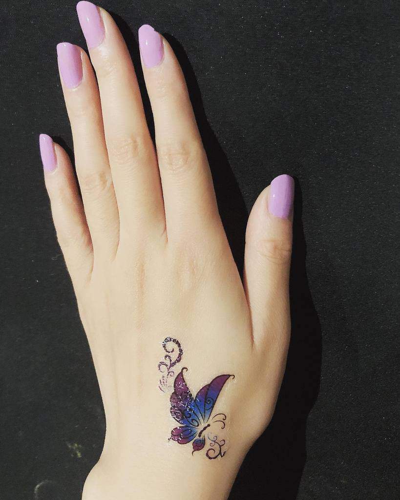 A hand with a colorful butterfly tattoo on the back