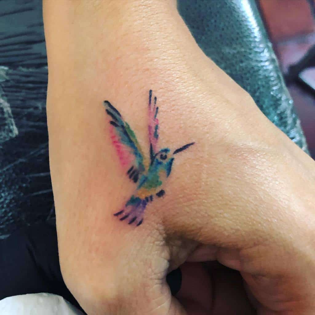A colorful hummingbird tattoo on a woman's hand