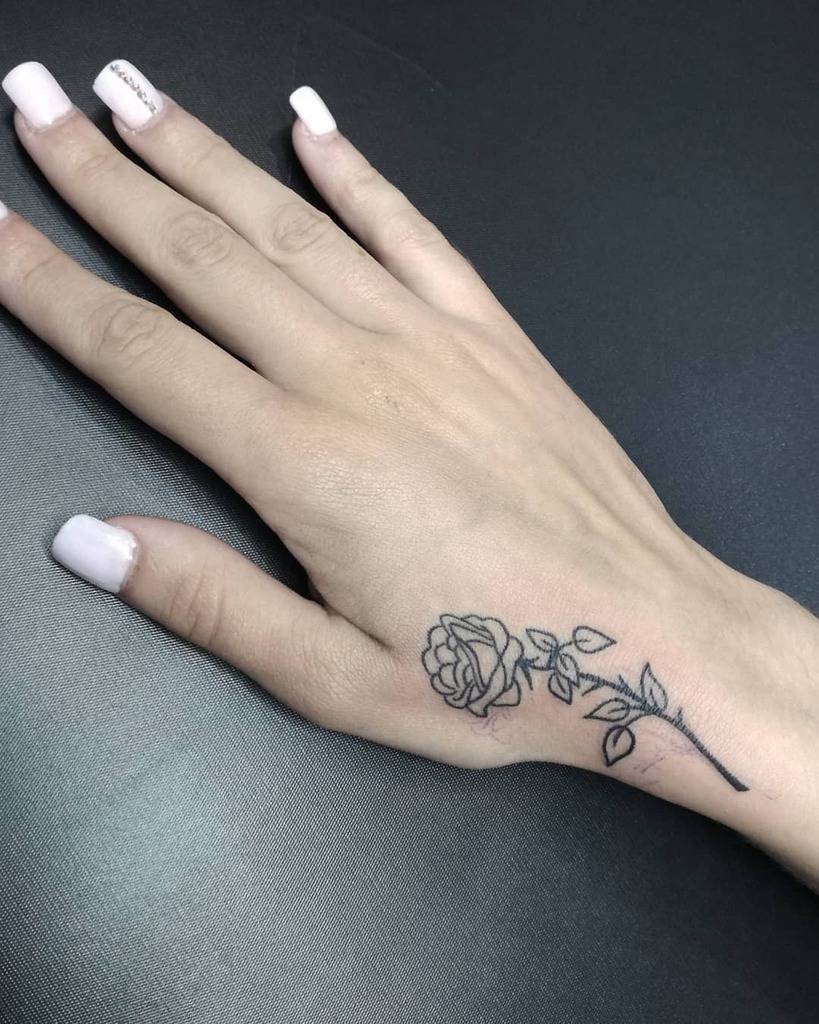 Hand with a black rose tattoo on the back