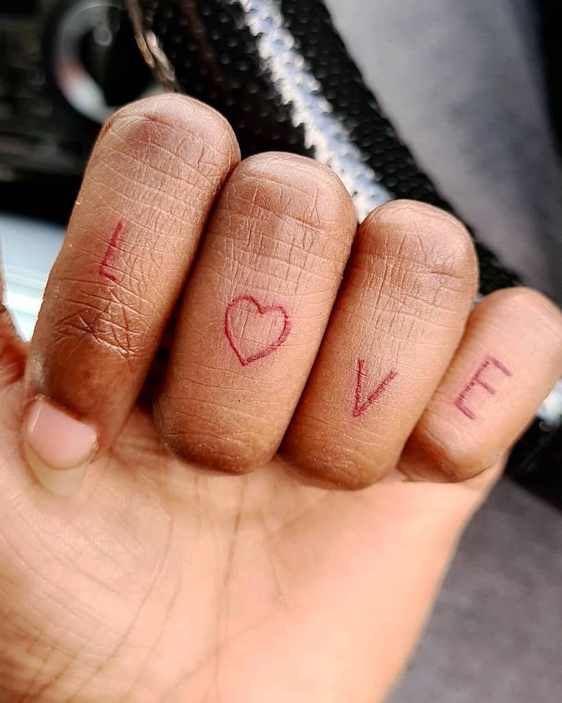 Fingers with "LOVE" drawn in red on each knuckle