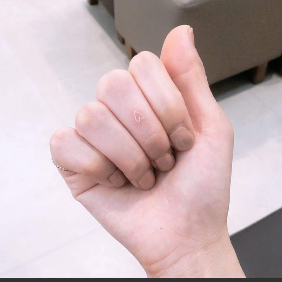 Hand with a tiny heart tattoo on the finger