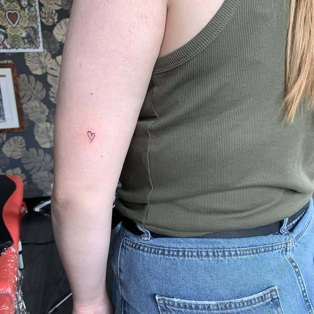 Small heart outline tattoo on the back of the upper arm